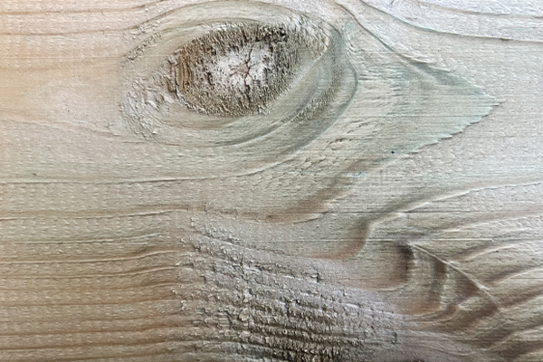 Helle Holzfläche mit ausgeprägtem Astloch oben links, sichtbarer Jahresring- und Holzmaserung, feine horizontale Riefen und raue Textur, natürliche Farbnuancen in Beige bis Hellbraun