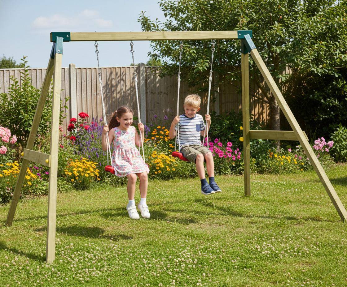 Doppelschaukel Alia Zwei Kinder (Mädchen links, Junge rechts) schaukeln auf roten Sitzen an einer hölzernen Doppelschaukel Alia im sonnigen Garten vor buntem Blumenbeet und Holzsichtschutzzaun
