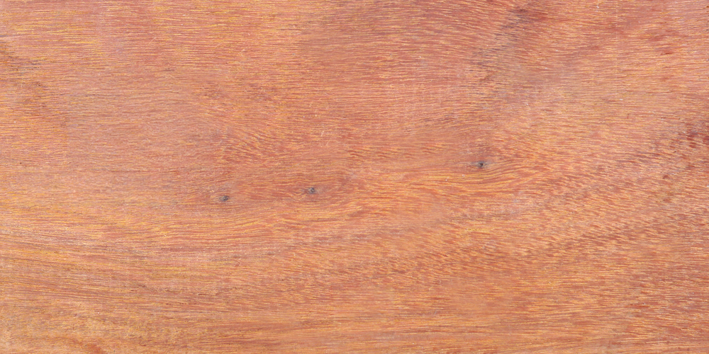 Rötlich-braune Holzplatte mit feiner horizontaler Maserung, dezenten Jahresringen und zwei kleinen dunklen Astlöchern