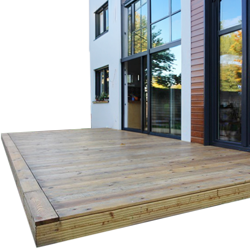 Holz-Terrassendielen auf erhöhtem Podest vor modernem Haus mit großen Glasfronten, naturfarbene Dielen mit sichtbaren Fugen, sichtbare Terrassenkante und Fensterreflexionen von Bäumen
