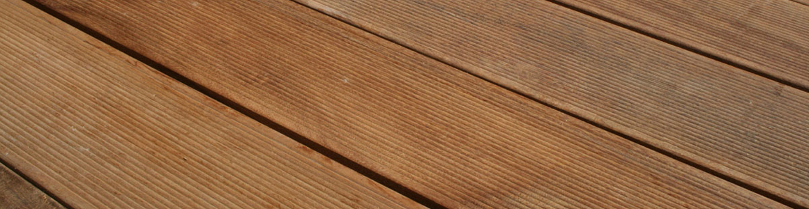 Nahaufnahme diagonal angeordneter Terrassendielen aus Holz mit feinen Längsrillen, warmbrauner Farbe und sichtbarer Maserung