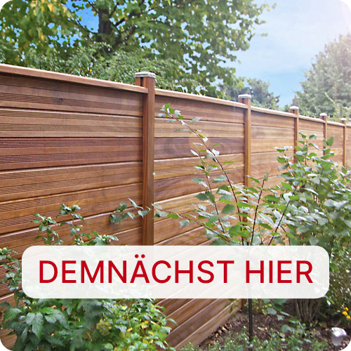 Holzzaun aus horizontalen Brettern mit Pfosten im Garten, Sträucher und Bäume davor und dahinter, weißes abgerundetes Schild mit roter Aufschrift DEMNÄCHST HIER