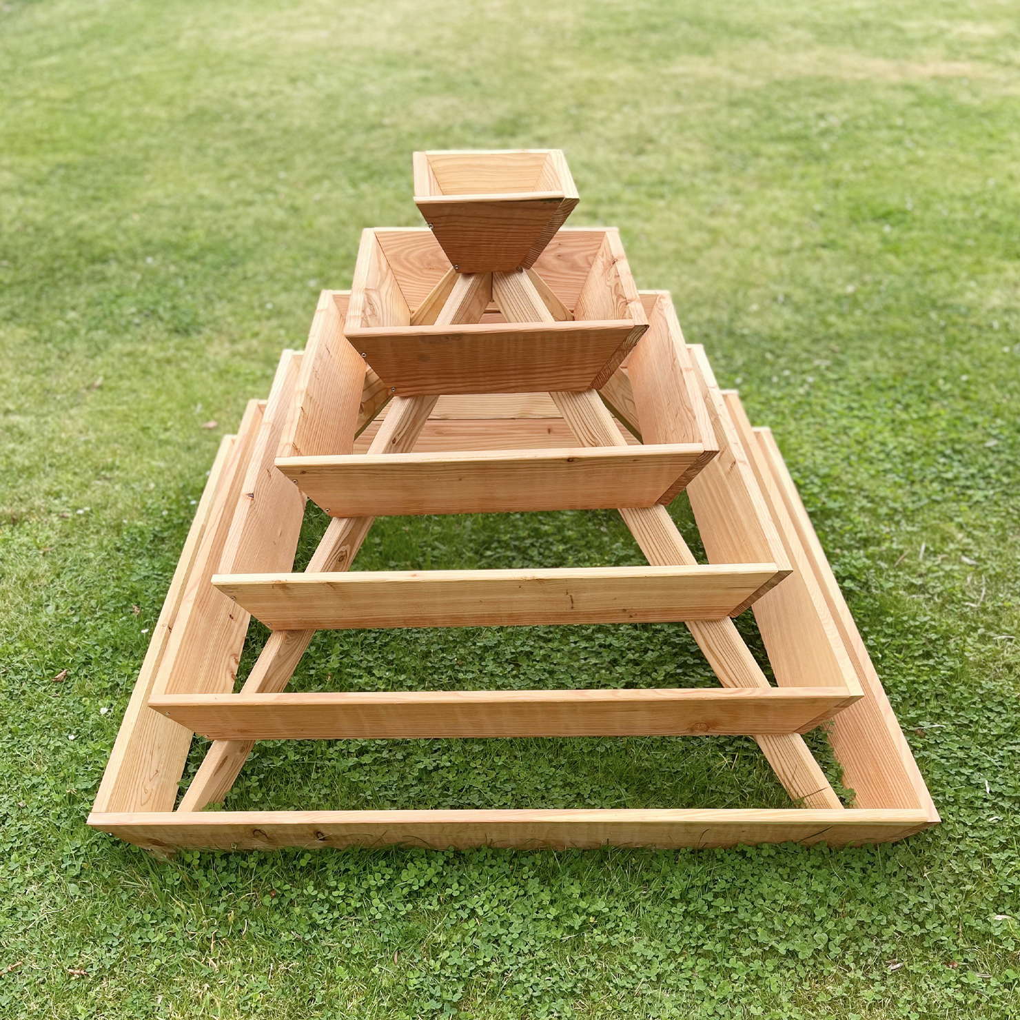 Holzpyramide zur Bepflanzung aus naturbelassener Lärche mit mehreren Ebenen, auf Rasen stehend; Maße 120 x 120 x 87 cm; geeignet für Kräuterbepflanzung, Pyramidengestaltung für Garten- oder Terrassennutzung.