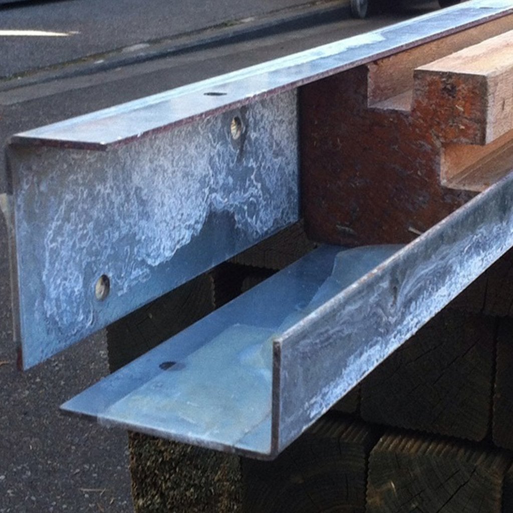 Winkelanker zum Einbetonieren aus Metall, Maße 550 x 80 x 40 mm, Detailansicht Winkelanker aus Metall zum Einbetonieren, Maße 550 x 80 x 40 mm, Ansicht von nah mit sichtbaren Befestigungslöchern und Holzleiste, im Außenbereich aufgeständert