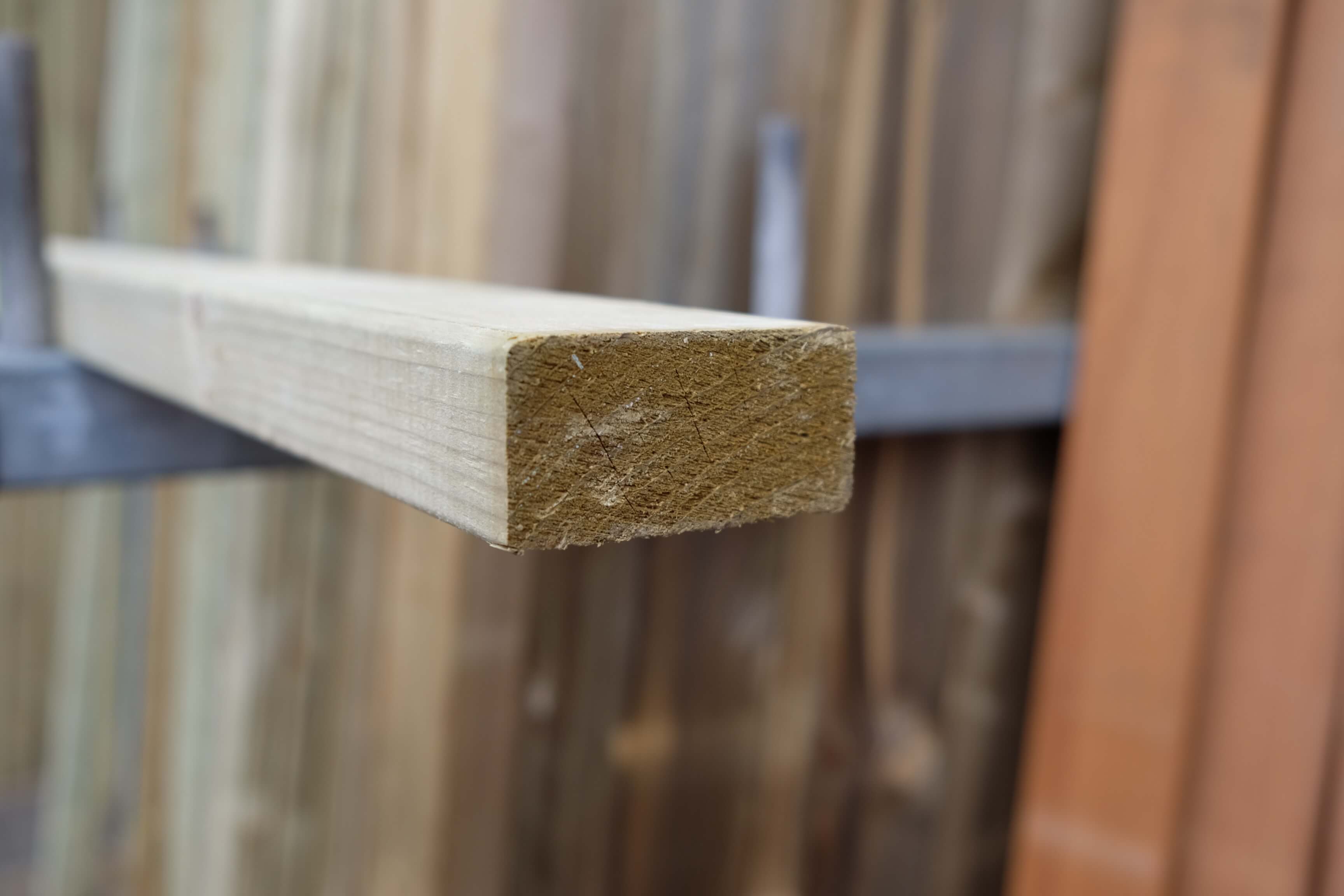 Konstruktionsholz glatt gehobelt und gefast, 20x45 mm, kesseldruckimprägniert Nahaufnahme eines glatt gehobelten, gefasten Konstruktionsholzes mit den Maßen 20x45 mm, kesseldruckimprägniert, vor unscharfem Hintergrund mit weiteren Holzlatten