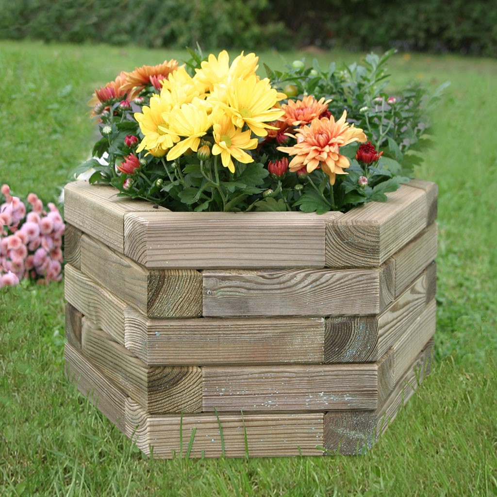 Pflanzkasten Stella sechskant, Kiefernholz Holz-Pflanzkasten aus gestapelten Balken mit gelben und orangefarbenen Chrysanthemen und grünem Laub auf Rasen im Garten